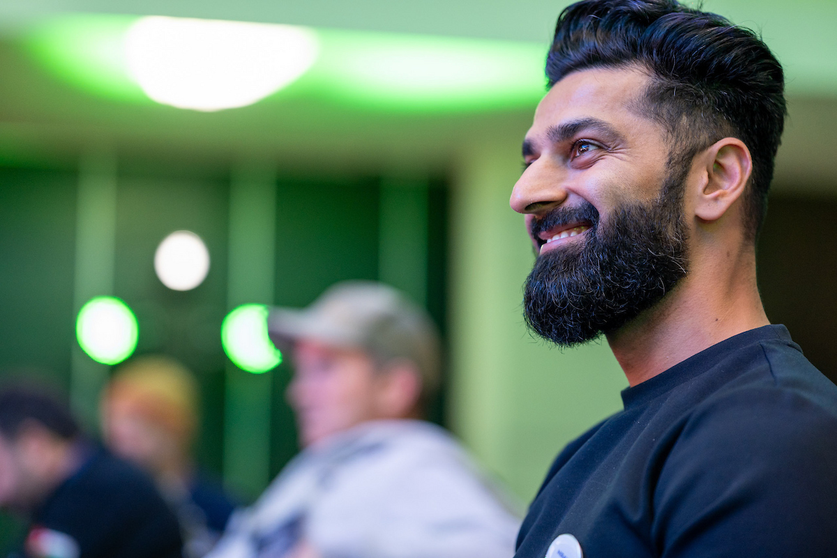 A male CEO smiles energetically while watching a presentation.