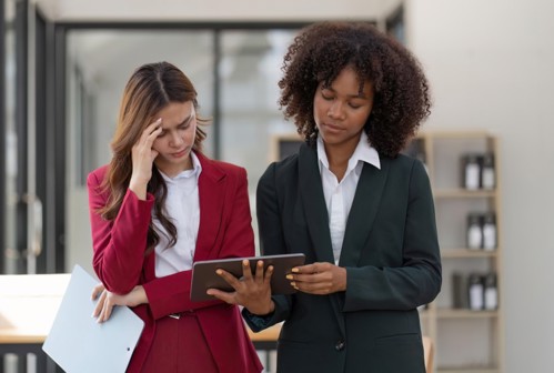 Two professional women look concerned about an online report.