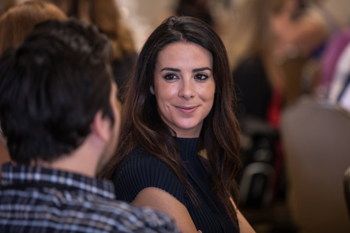 A woman in business attire with an inquisitive smile