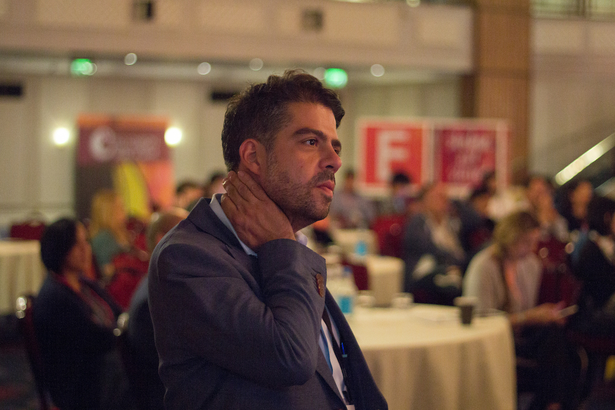 A male entrepreneur in business attire rubs his neck as if he is stressed.
