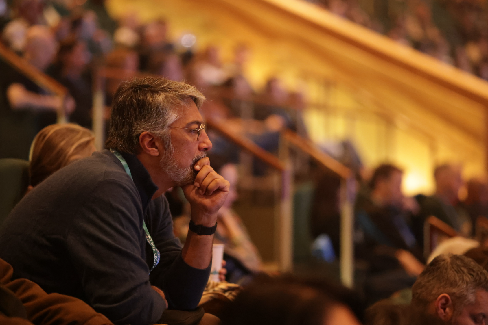 Thoughtful man sits in a presentation with head in his chin.