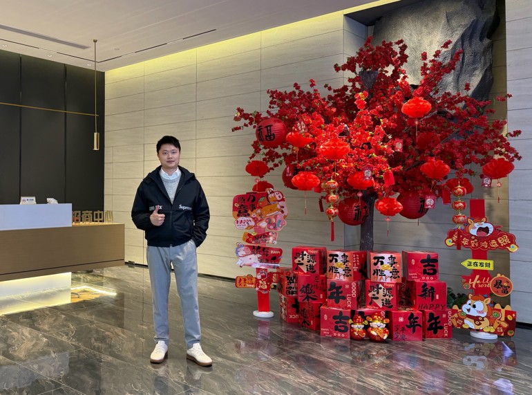 A Chinese entrepreneur stands in a festively decorated lobby.