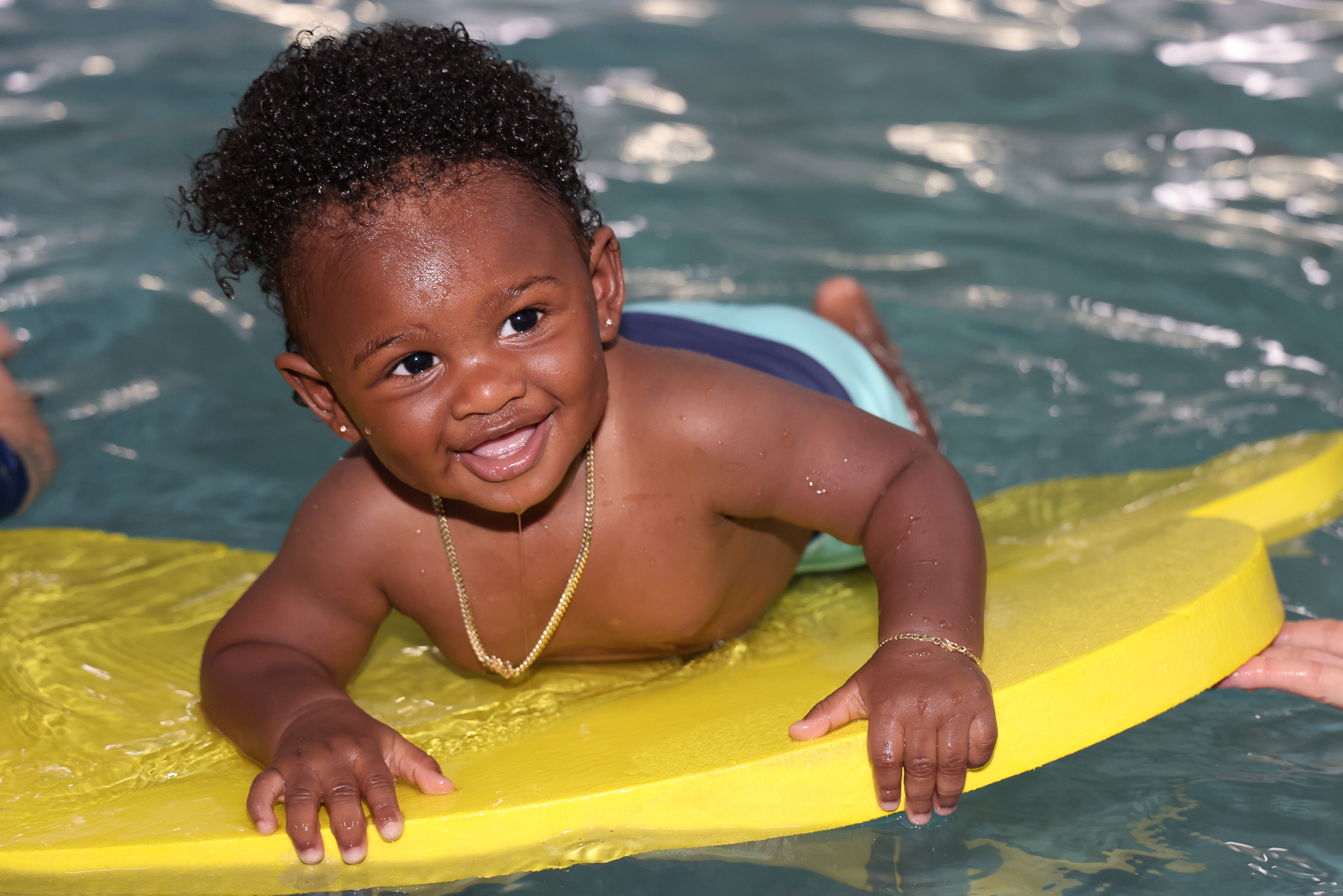 A toddler smiles on a swim float during a swimming lesson.