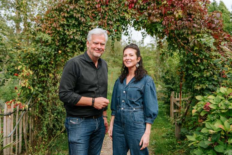 A male and female entrepreneur stand together in an outdoor garden.