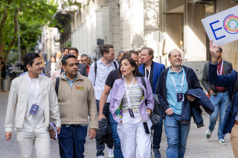 A group of EO leaders at a meeting walk together along a sunny street.