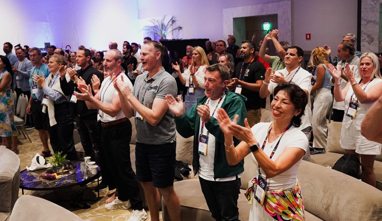 A room full of dozens of entrepreneurs standing and applauding.