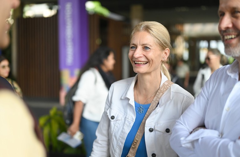A woman in conversation with two business people smiles engagingly.
