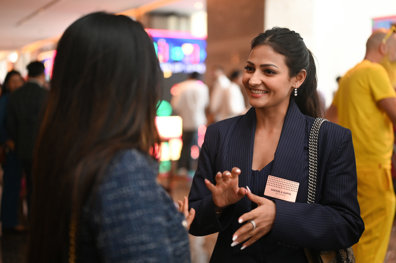 Two women in business attire make eye contact in a genuine, authentic conversation.