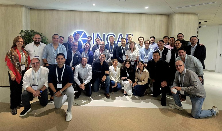 About 50 entrepreneurs in business attire pose with INCAE signage.