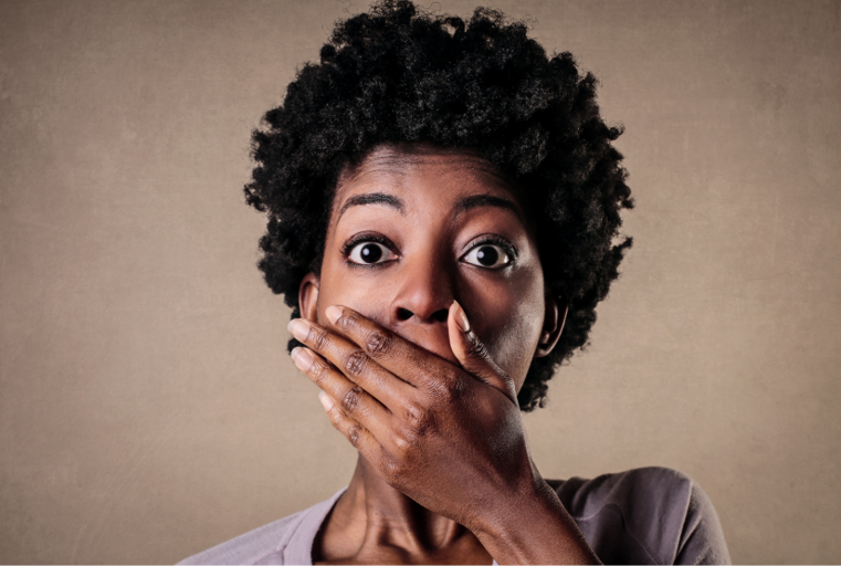 A professional Black woman holds her hand over mouth in surprise.