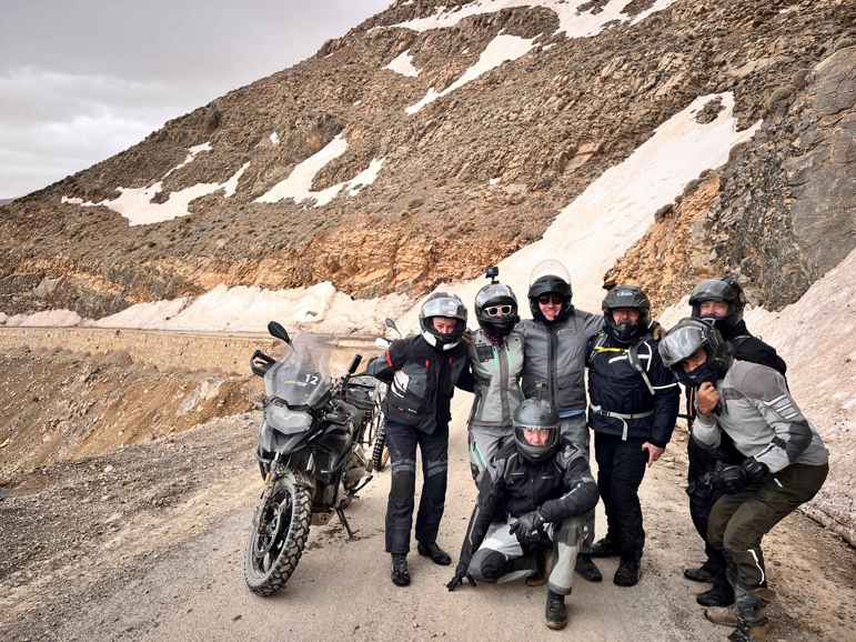 A group of seven motorcyclists on a dusty mountain trail.