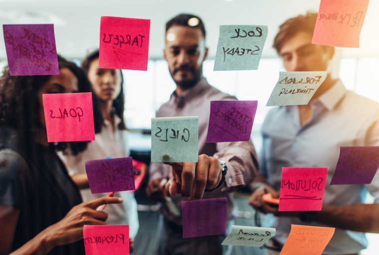 Company leaders study a wall covered with ideas on sticky notes.