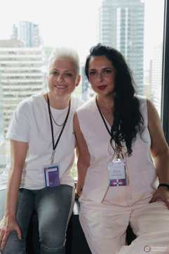 Two women pose in front of the Montreal skyline.