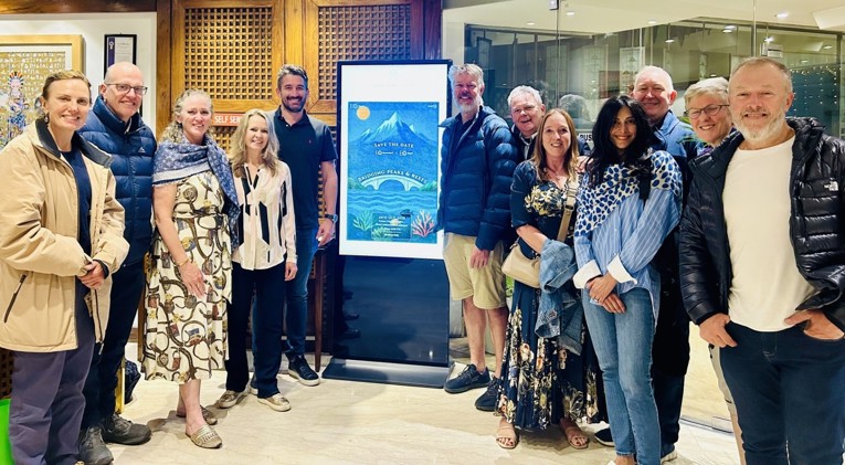 Twelve EO members stand next to a sign welcoming them to EO Nepal.