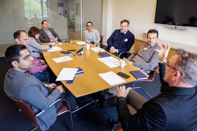 Eight business leaders around a boardroom table have an intense discussion