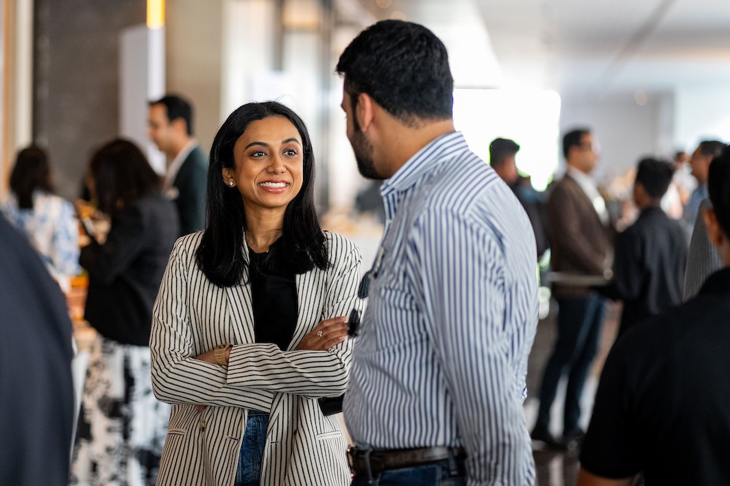 A woman in business attire smiles confidently at a colleague.