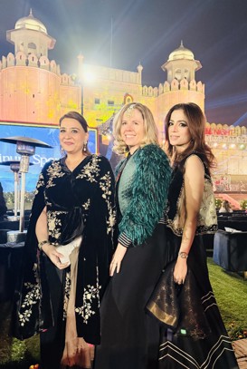 Three women in evening attire stand before a beautiful castle in Lahore, Pakistan.