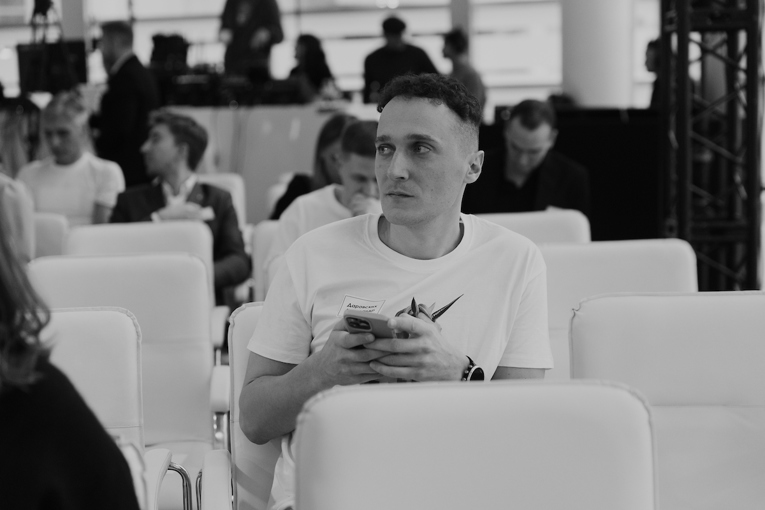 A worried man looks off into the distance while holding his phone.