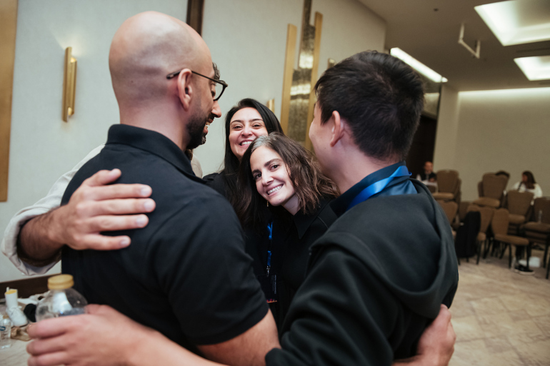 Four entrepreneurs give each other a group hug of support.