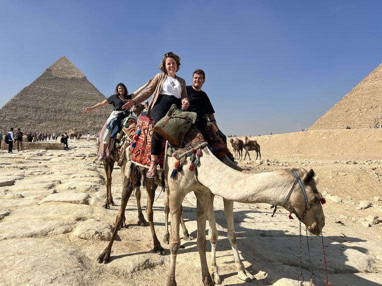 A woman on a camel with the Egyptian pyramids in the background.