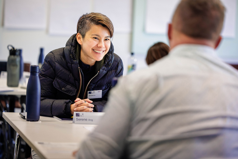 A young entrepreneur sits across from an older entrepreneur in a mentoring stance.