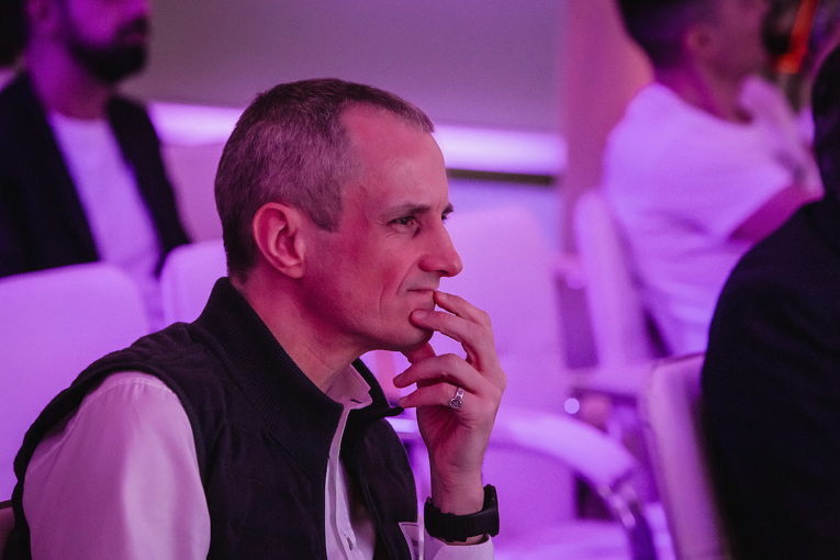 A man with a pensive expression on his face rests his hand on his chin.