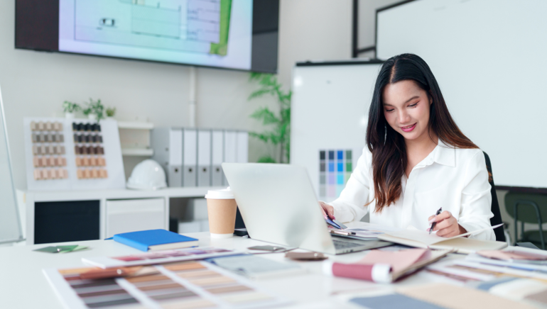 A female business owner reviews files on her organized but busy desk.