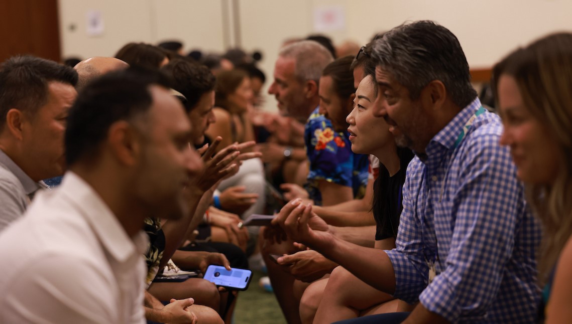 A group of seated founders share ideas across a makeshift aisle.