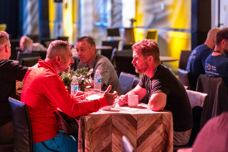 Two entrepreneurs enjoy a passionate conversation over coffee in a group setting.