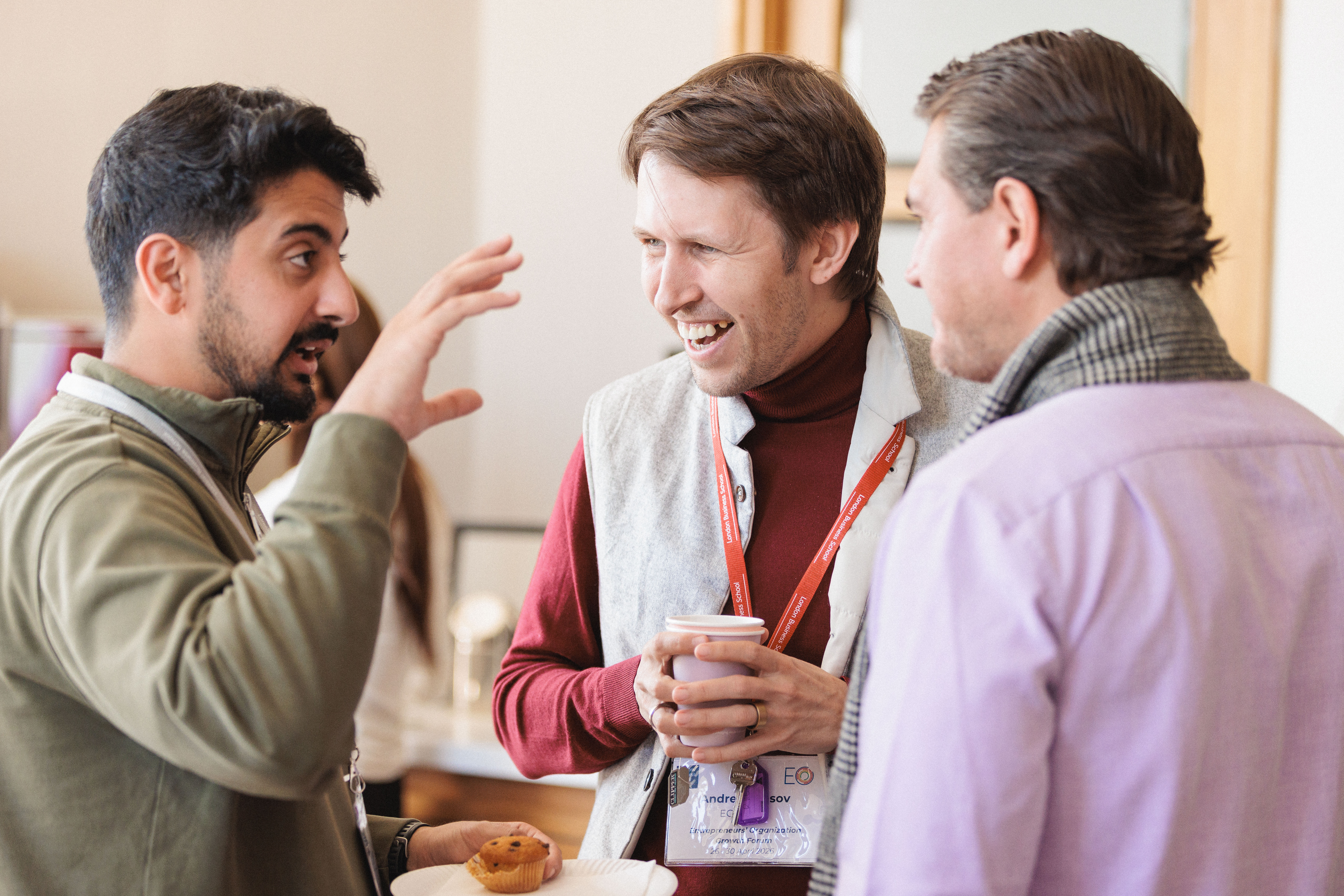 Three male entrepreneurs in business casual clothing have a lively discussion.